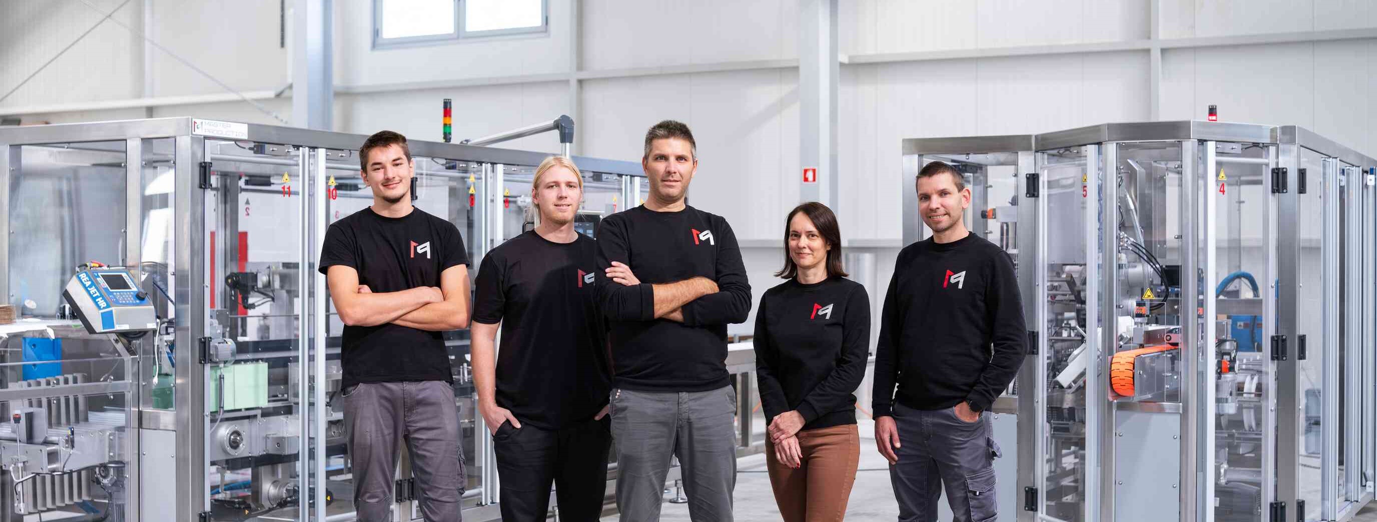 Ein Teil des Master Production-Teams stolz vor seiner horizontalen Kartoniermaschine